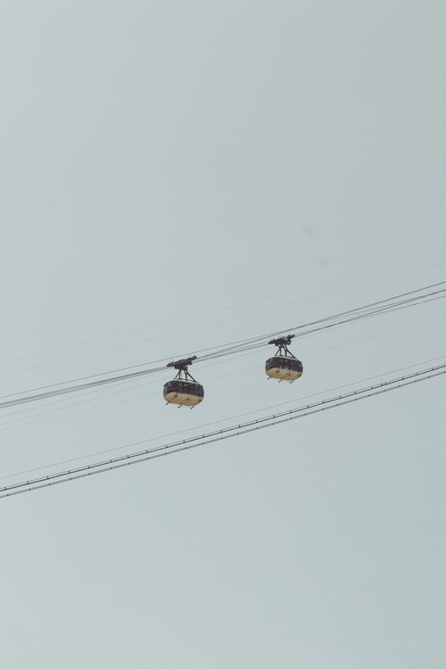 Free Two cable cars suspended in the sky on a clear day, showcasing transportation technology. Stock Photo