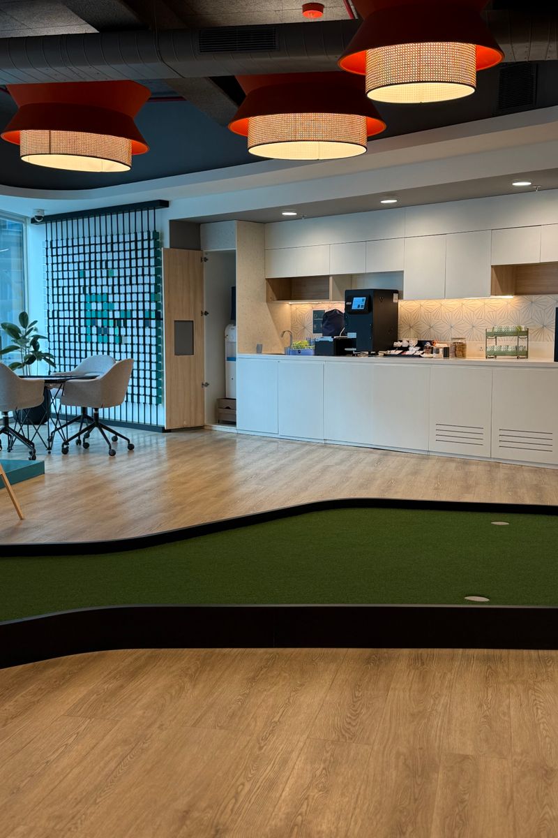 Cozy office lounge area with indoor putting green and seating for relaxation and meetings.