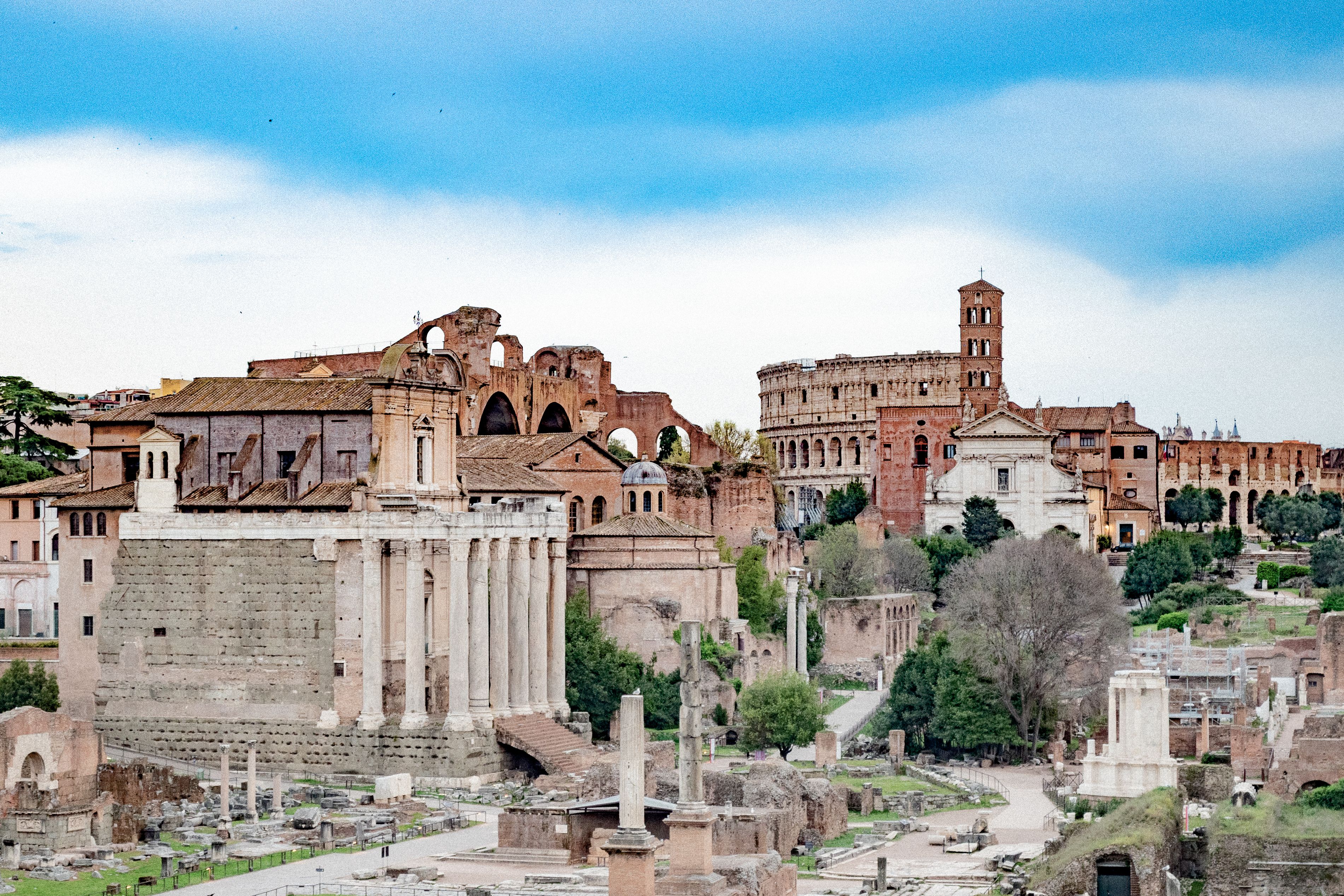 Explore the grandeur of Roman Forum with its iconic ancient structures under a bright, clear sky.