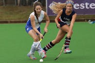 两名女子曲棍球运动员在绿意盎然的球场上激烈比拼