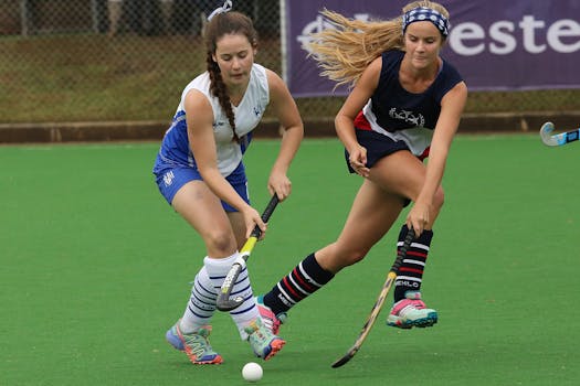 两名女子曲棍球运动员在绿意盎然的球场上激烈比拼