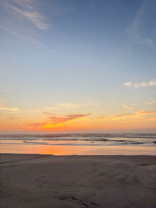 Free Captivating beach sunset with a golden sky and tranquil waves, ideal for relaxation themes. Stock Photo
