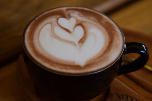 Close-up of beautiful latte art in a black coffee mug. Perfect for coffee enthusiasts and cafe ambiance.