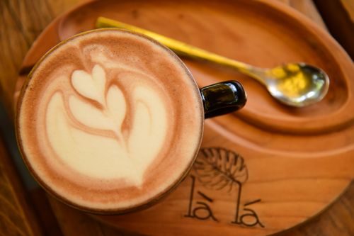 Free Intricate latte art coffee on a wooden tray with a spoon, in a cozy cafe setting. Stock Photo