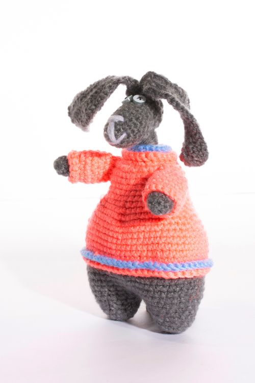 Free A playful crocheted dog toy dressed in a vibrant orange sweater with blue accents, perfect for kids' playtime. Stock Photo