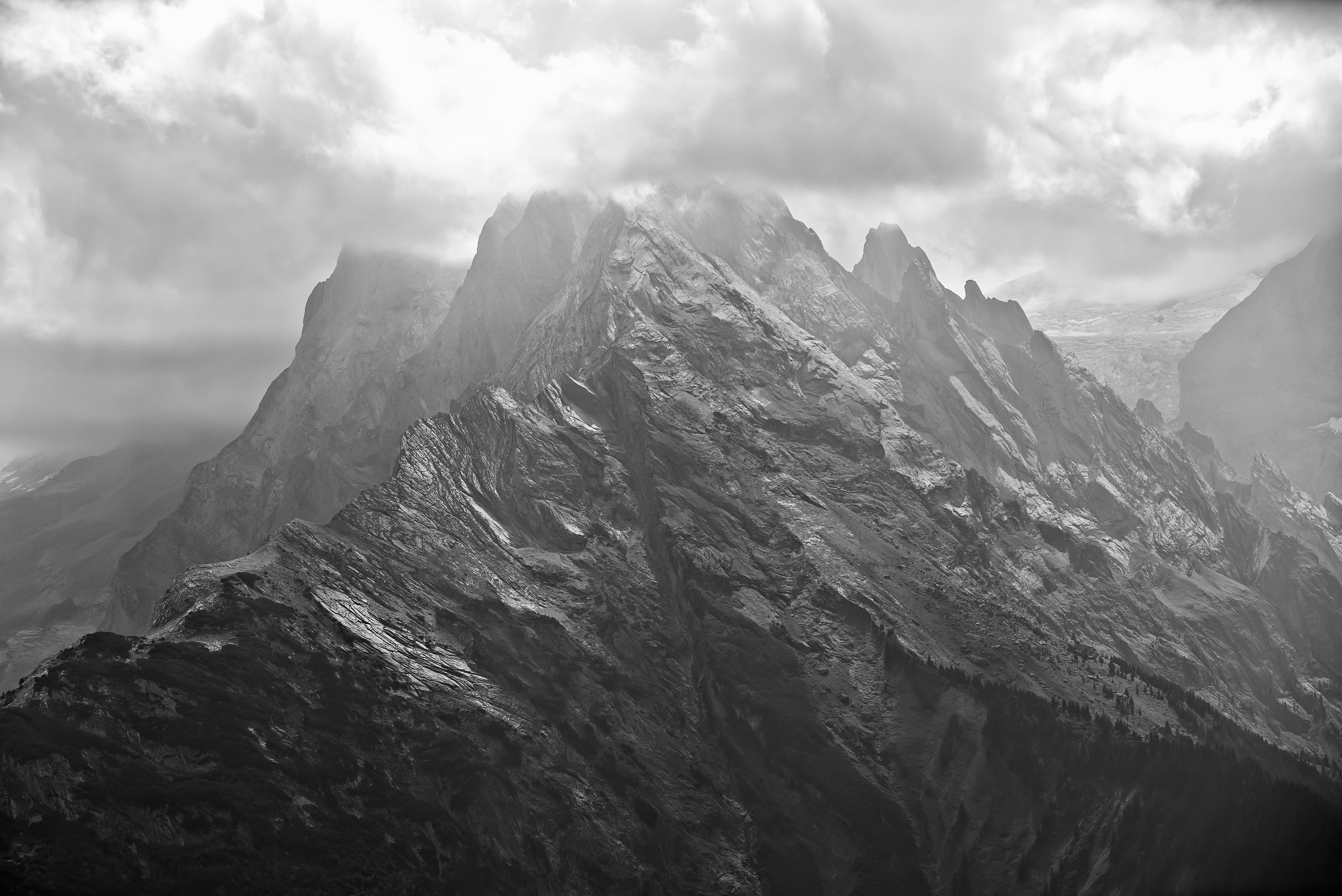 Striking black and white image of a rugged mountain peak under moody clouds.