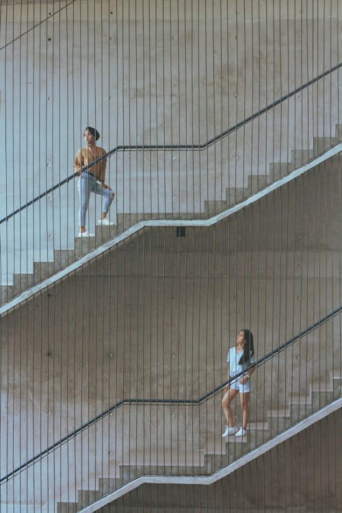 Man in T-shirt and Blue Denim Jeans Walking Up the Stairs