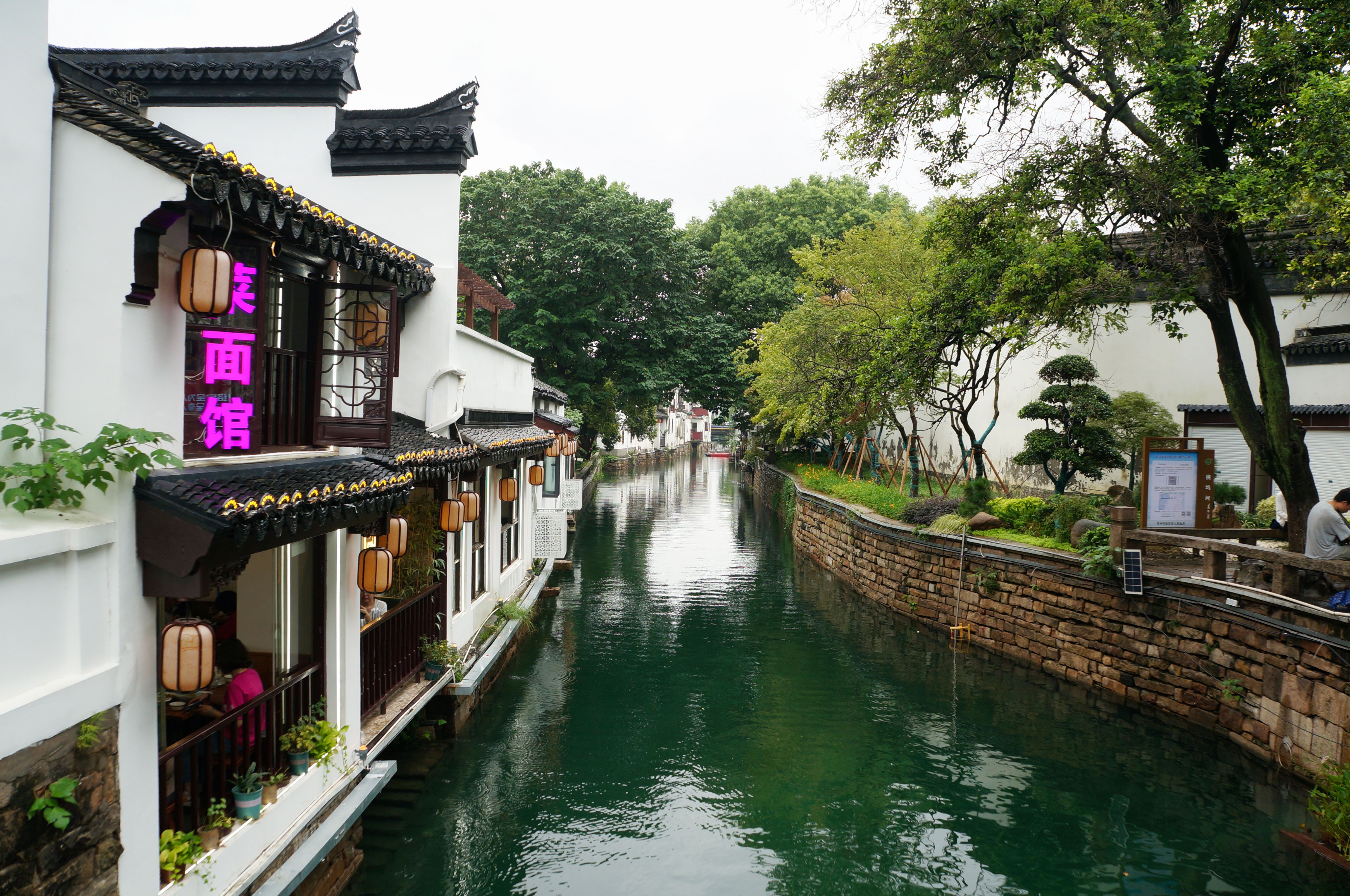 Traditional Suzhou architecture along a tranquil canal, blending history and nature.