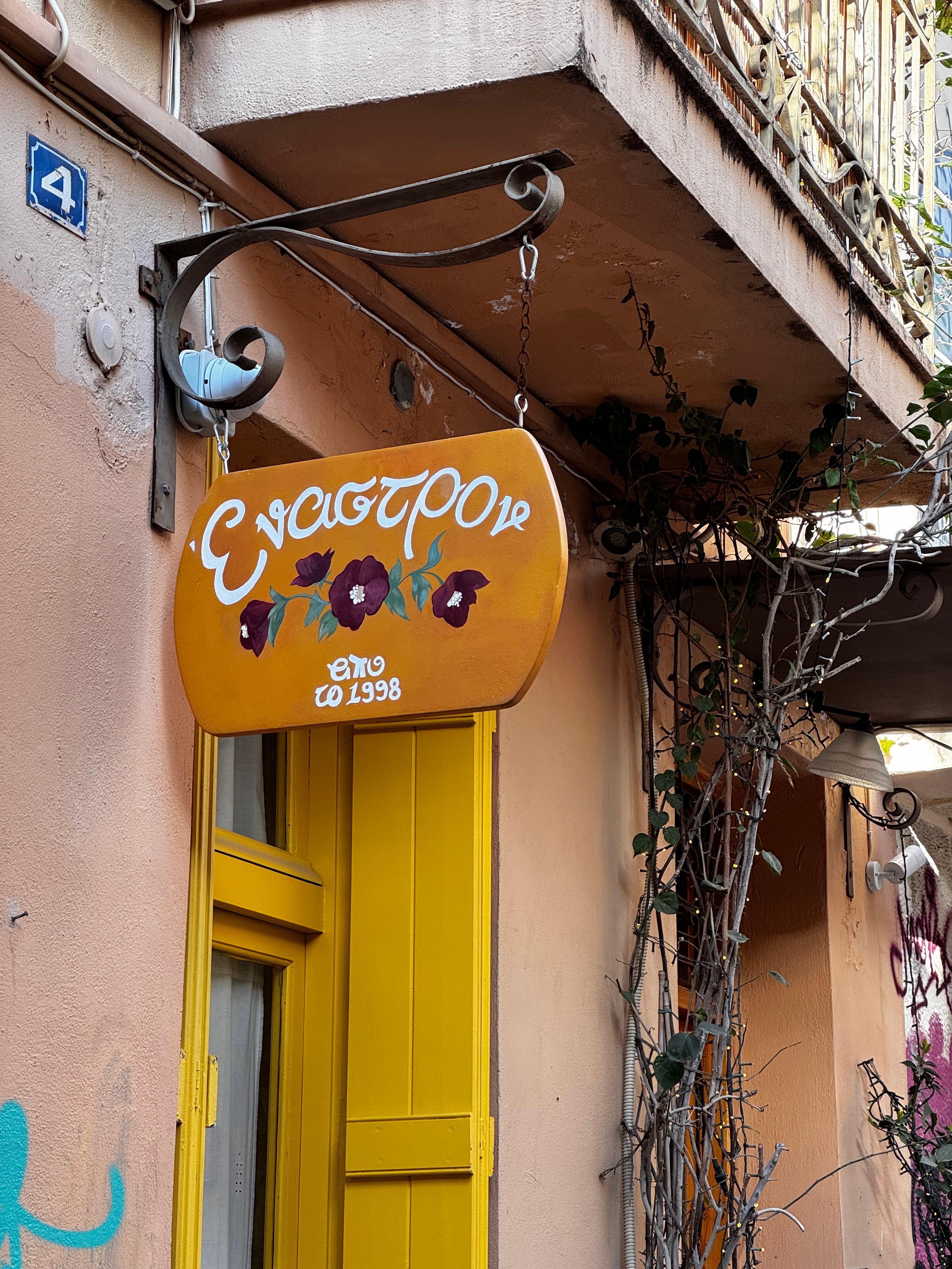 A quaint street corner in Athens, Greece, featuring a colorful Greek sign and rustic charm.