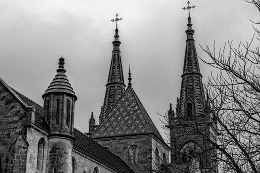 Black and white image of the towering Gothic spires of Neuchâtel Cathedral against a winter sky.