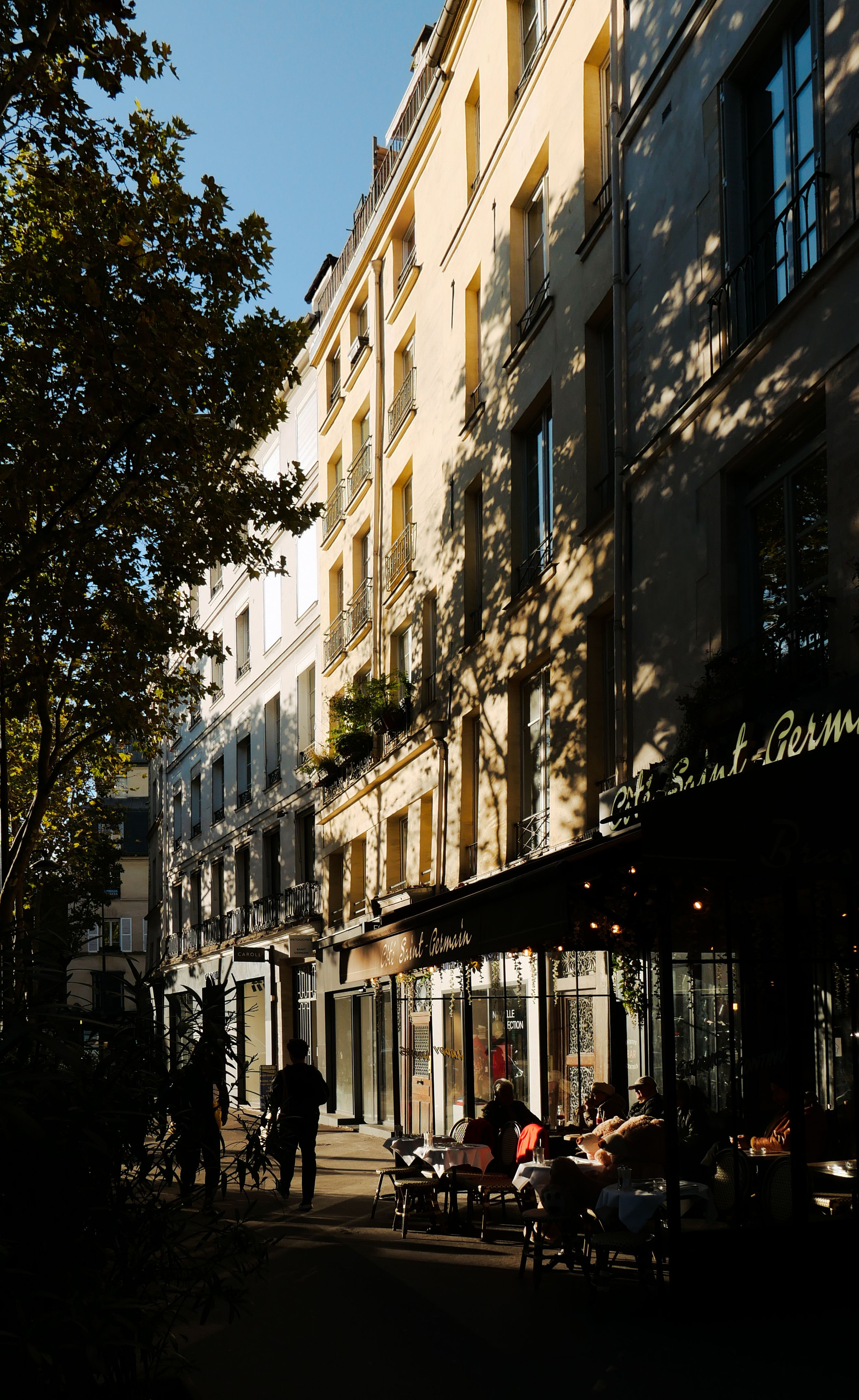 A vibrant Parisian street scene featuring a café with patrons enjoying the sunny day.