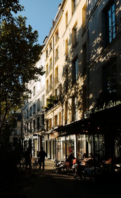 A vibrant Parisian street scene featuring a café with patrons enjoying the sunny day.