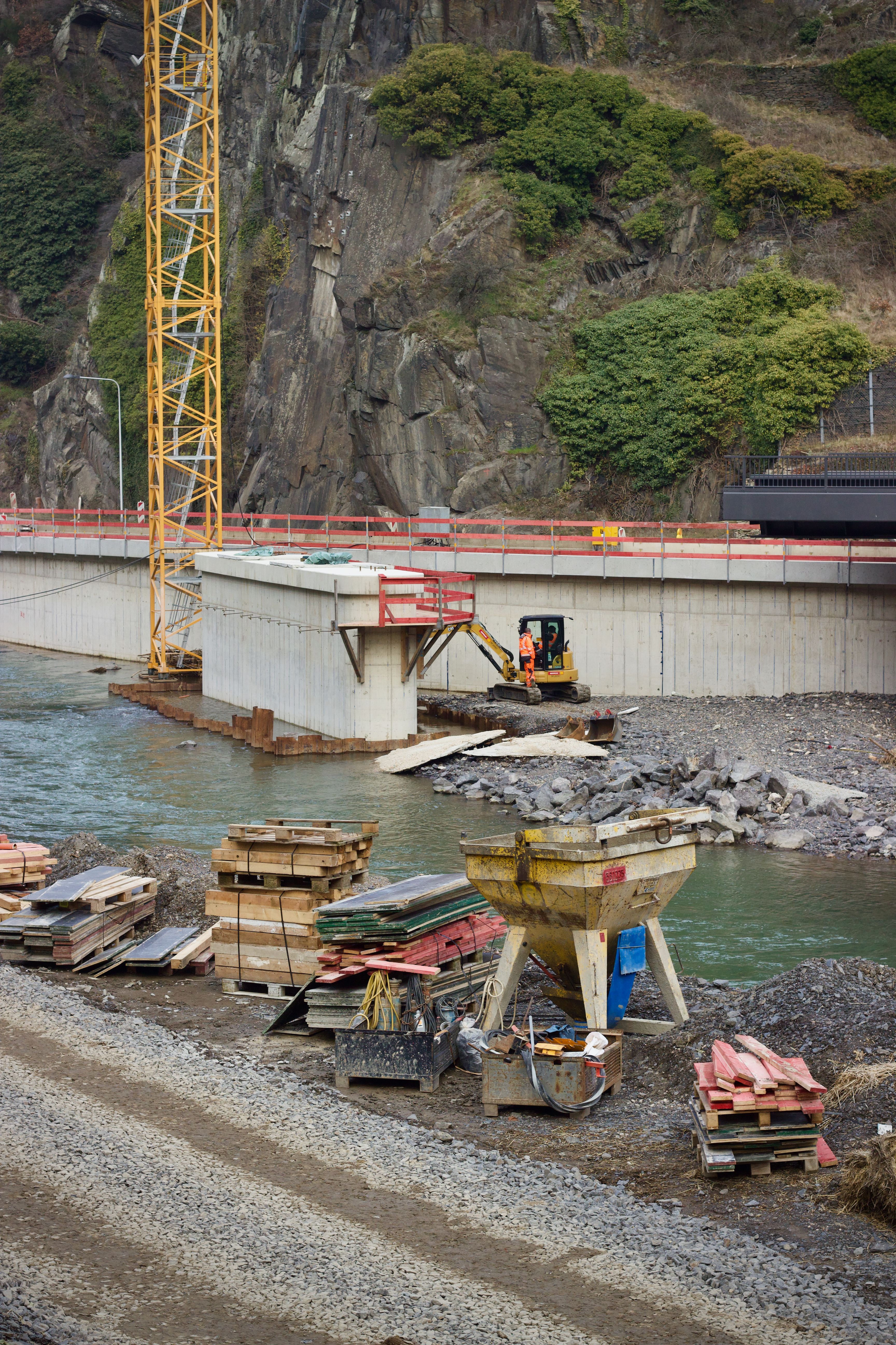 Construction Site by River and Cliff with Equipment · Free Stock Photo