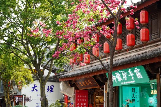Vibrant street scene in Dali, China, featuring cherry blossoms and traditional Chinese lanterns.
