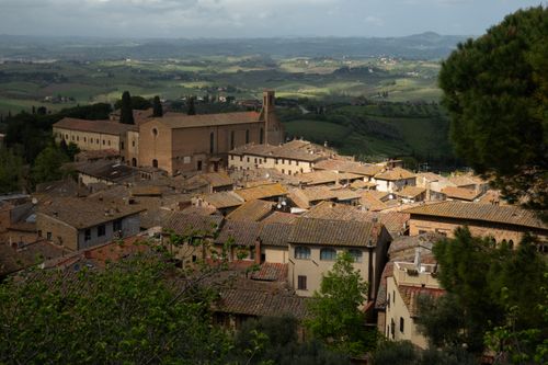 Free Aerial view of historical Tuscan rooftops and countryside, capturing serene rolling hills and rustic architecture. Stock Photo