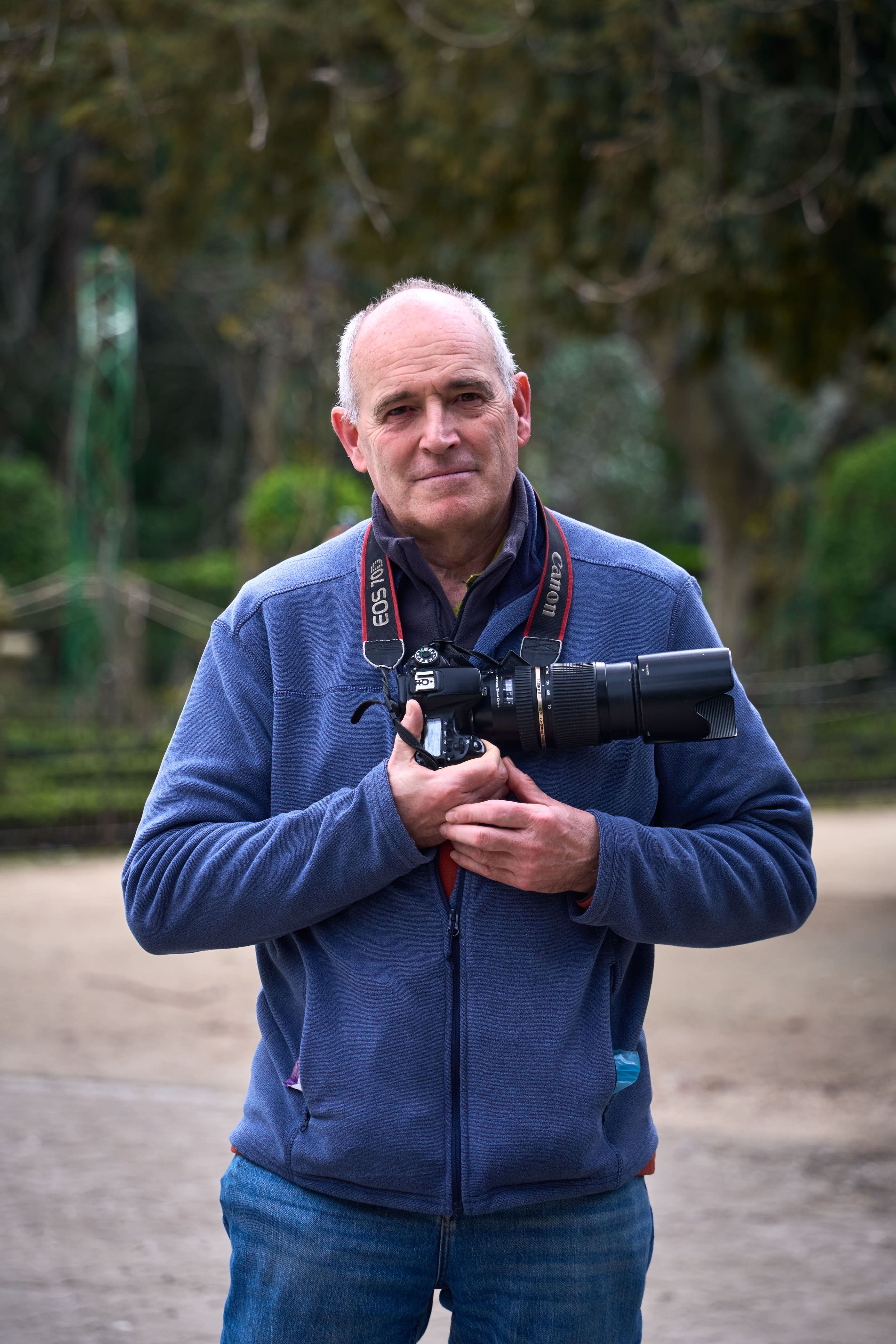 Portrait of a photographer in a public park in Valladolid, Spain, holding a DSLR camera.