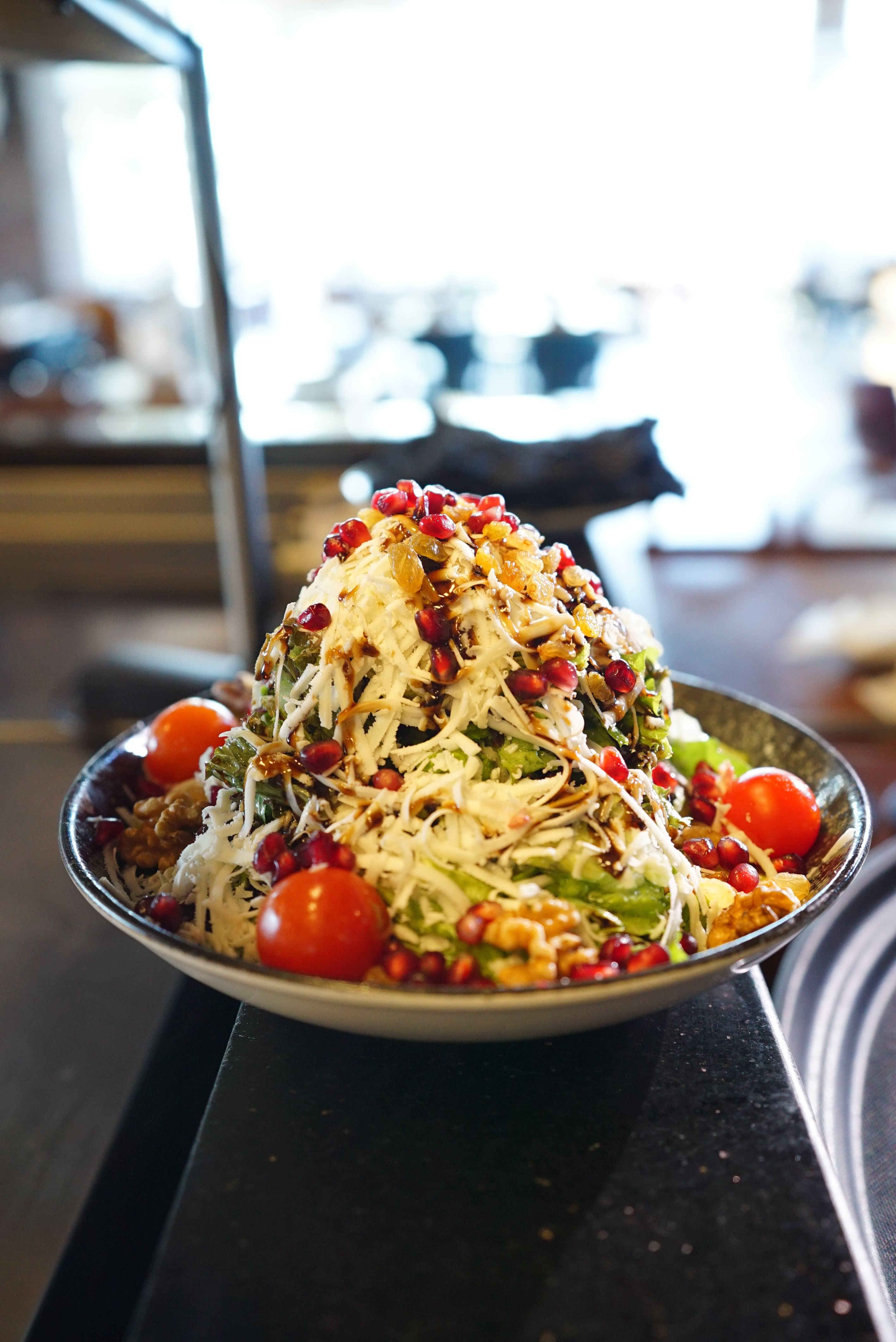 Colorful Mediterranean salad topped with pomegranate, walnuts, and cherry tomatoes.