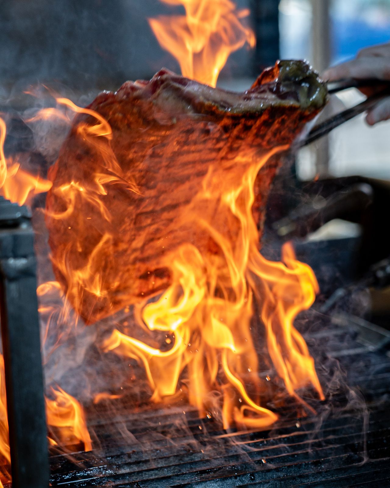 Steak grilling with flames at an outdoor barbecue