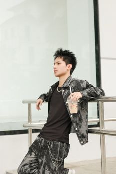 Fashionably dressed young man drinking iced coffee in an urban setting.