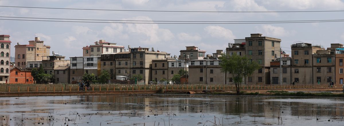 Reflection of urban buildings across a serene body of water on a sunny day.