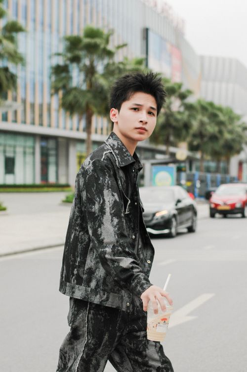 Free Stylish young man holding a drink while walking across a modern city street. Stock Photo