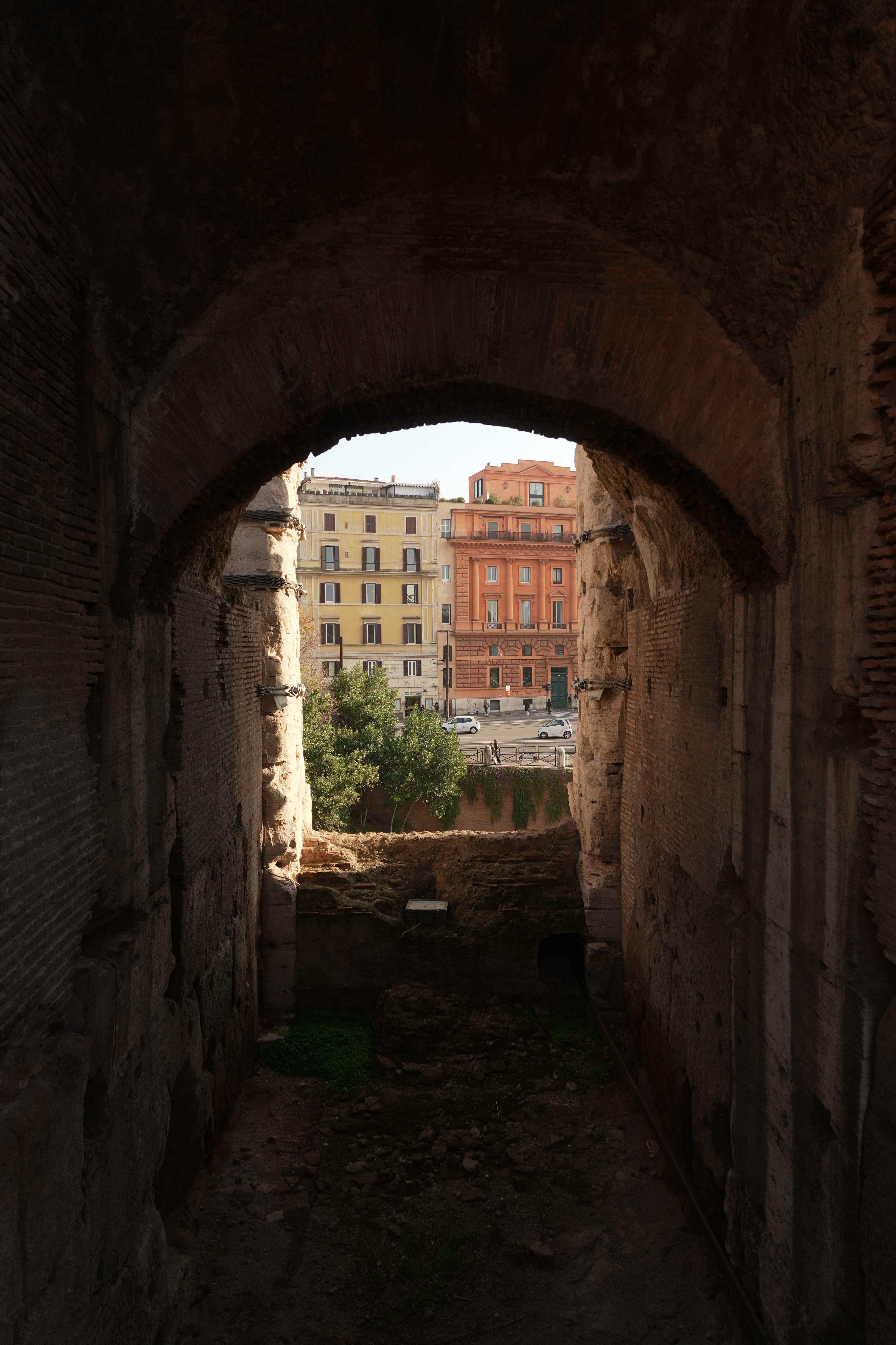 Explore the blend of ancient and modern architecture in Rome from inside a historic archway.
