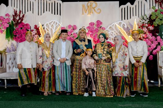 A vibrant traditional wedding ceremony with participants in ornate attire in Kendari, Indonesia.