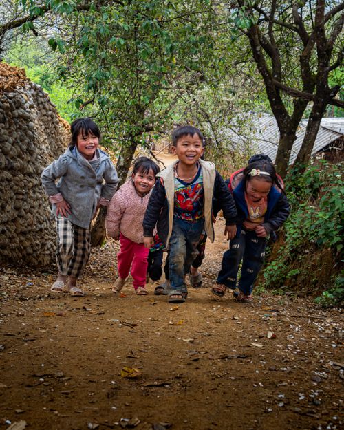 Free Smiling group of children enjoying a playful moment on a scenic dirt path surrounded by nature. Stock Photo
