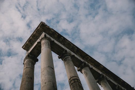 Explore the majesty of ancient Roman columns beneath a partly cloudy sky, captured in Italy.