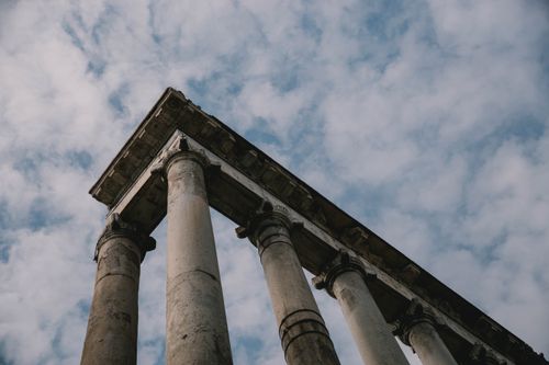 Free Explore the majesty of ancient Roman columns beneath a partly cloudy sky, captured in Italy. Stock Photo