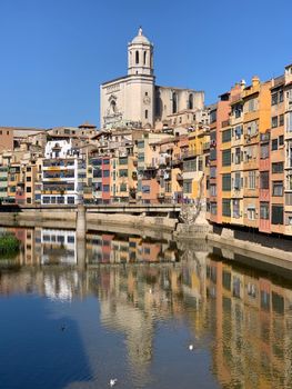 Vibrant riverside buildings in Girona with reflections in the Onyar River.