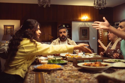 Free A lively family dinner with diverse group enjoying a meal and engaging in conversation. Stock Photo