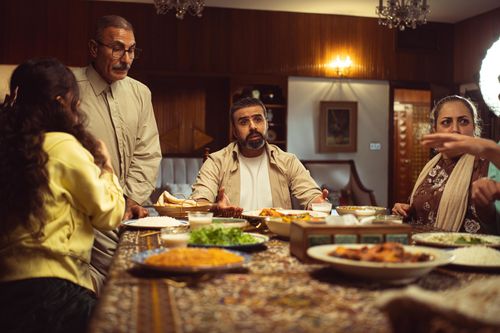 Free A family gathers around a dinner table in a cozy indoor setting, engaging in lively conversation. Stock Photo