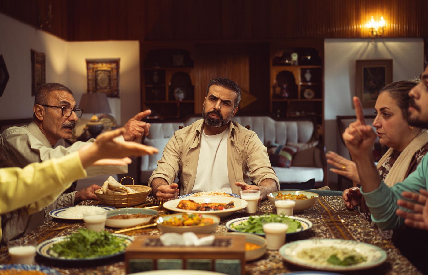 Family gathered around a dinner table, engaging in a lively conversation in a cozy dining room.