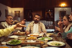 Family gathered around a dinner table, engaging in a lively conversation in a cozy dining room.