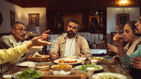 Family gathered around a dinner table, engaging in a lively conversation in a cozy dining room.