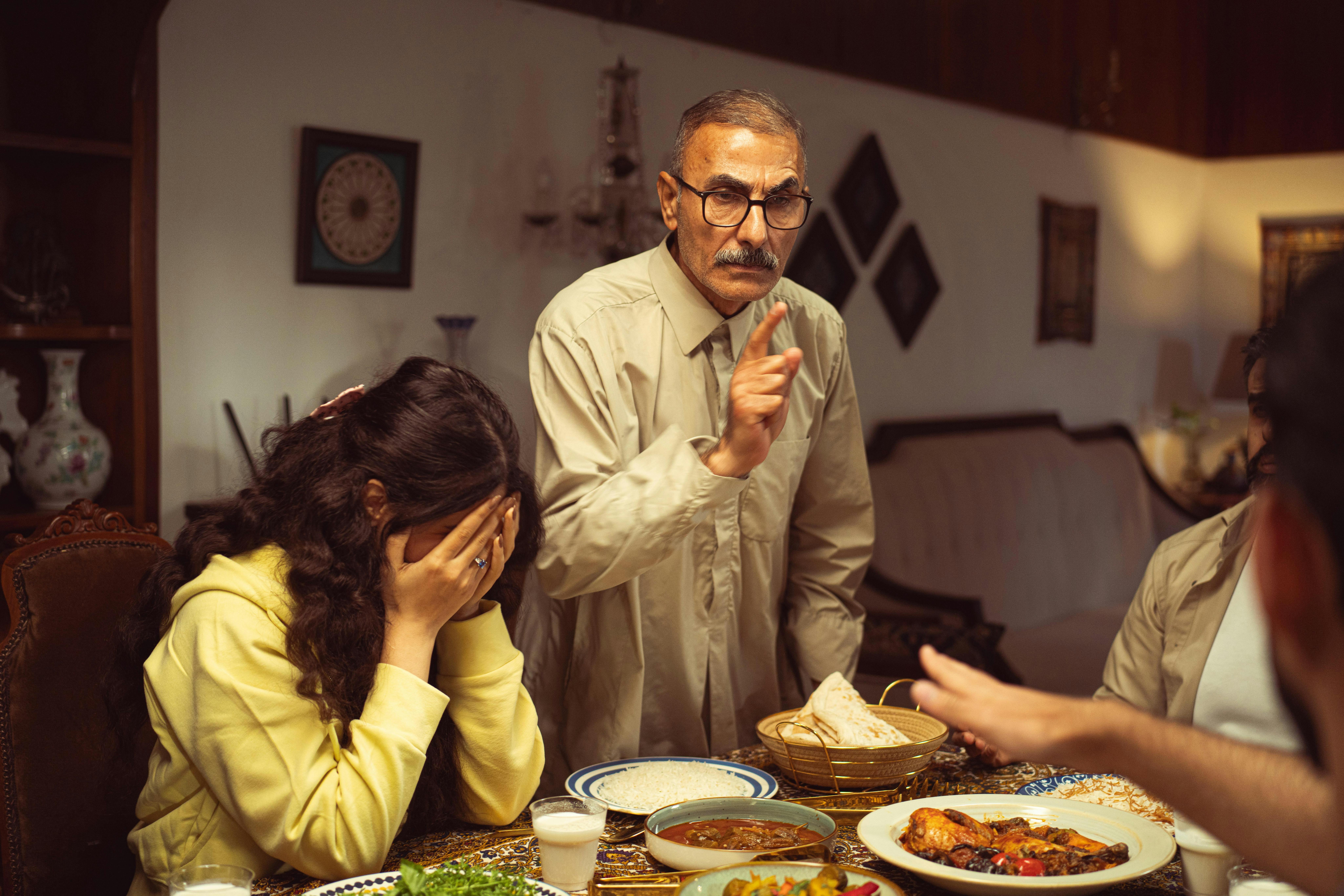 A tense moment with a family disagreement at the dinner table indoors.