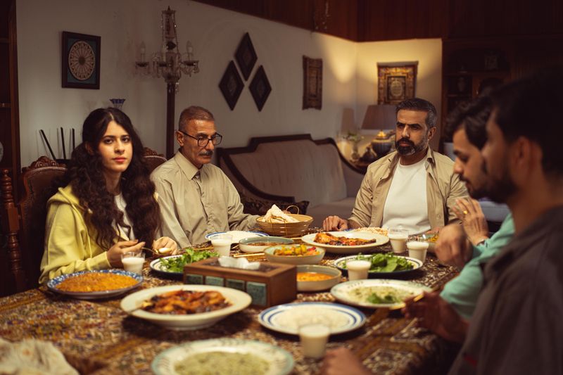 A family gathers at home for a traditional dinner, sharing diverse dishes and warm company.
