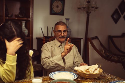 Free An elder man engages in a serious discussion during family mealtime inside a cozy home setting. Stock Photo