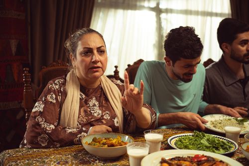 Free A family enjoys a traditional meal at home, sharing conversation and laughter around the dining table. Stock Photo