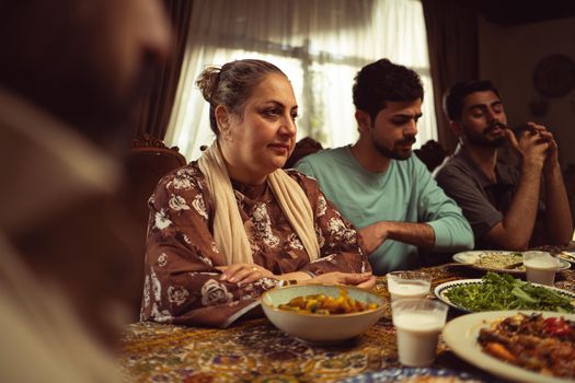 A heartwarming family scene enjoying a meal together indoors, showcasing cultural unity.