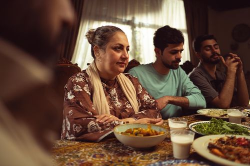 Free A heartwarming family scene enjoying a meal together indoors, showcasing cultural unity. Stock Photo