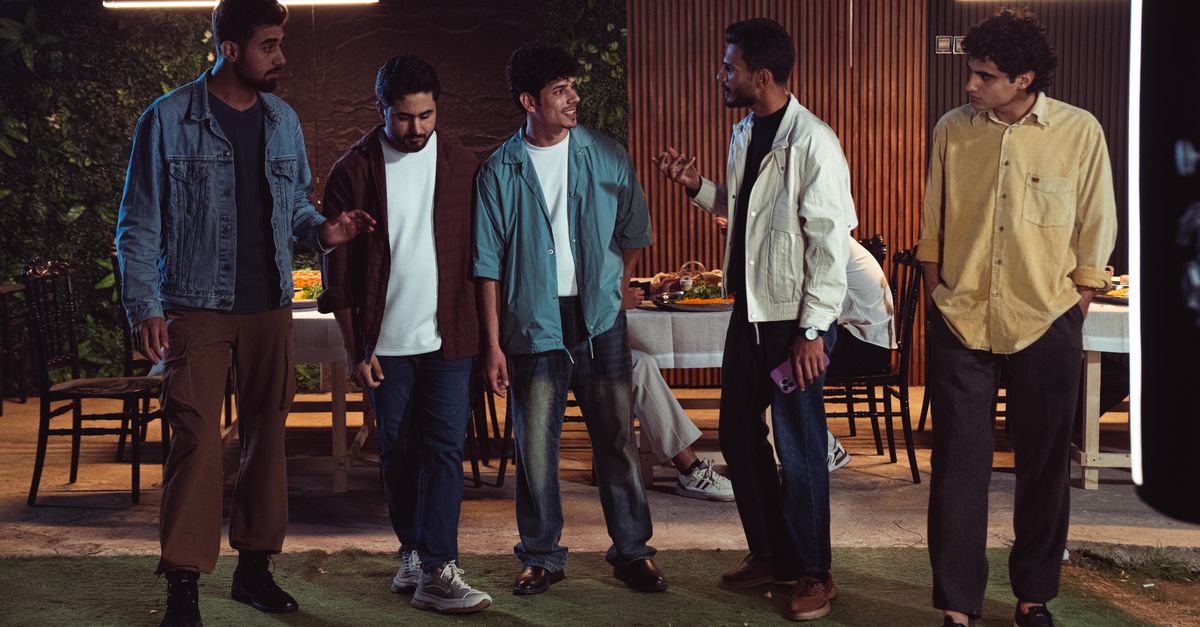 A diverse group of people laughing together at a dinner table, warm lighting