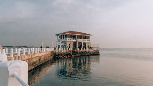 Free A peaceful view of Moda Pier in Istanbul as calm waters reflect the picturesque architecture against a cloudy sky. Stock Photo