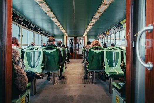 Passengers seated inside a Venetian vaporetto waterbus, captured from the interior view.