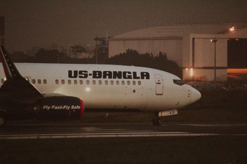 Free US-Bangla Airlines aircraft preparing for takeoff at dusk, showcasing air travel. Stock Photo