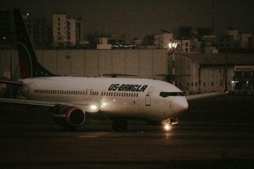 Free US-Bangla Airlines Boeing aircraft taxiing on runway during night at the airport. Stock Photo