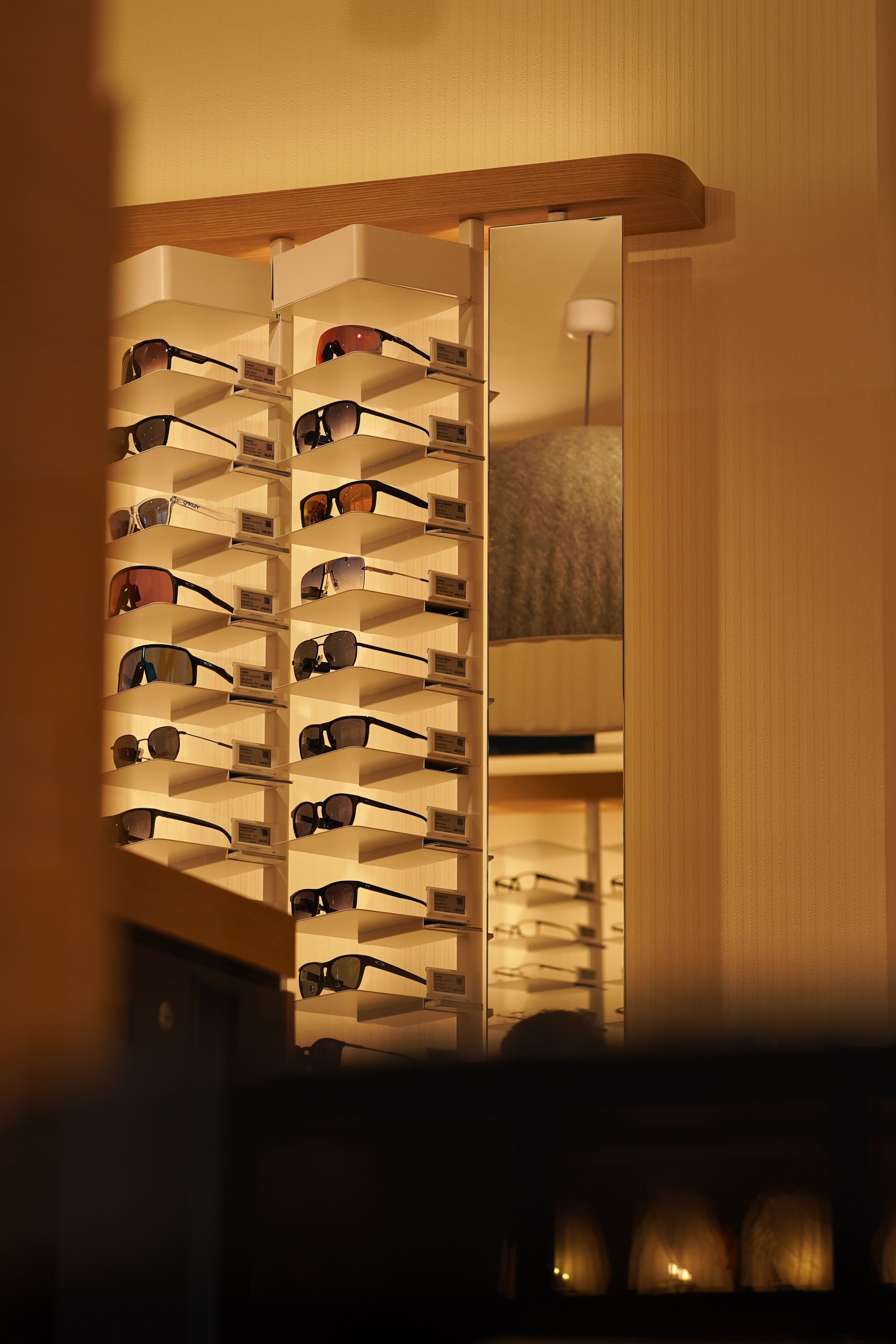 A modern display of various sunglasses in a fashionable store with warm lighting.