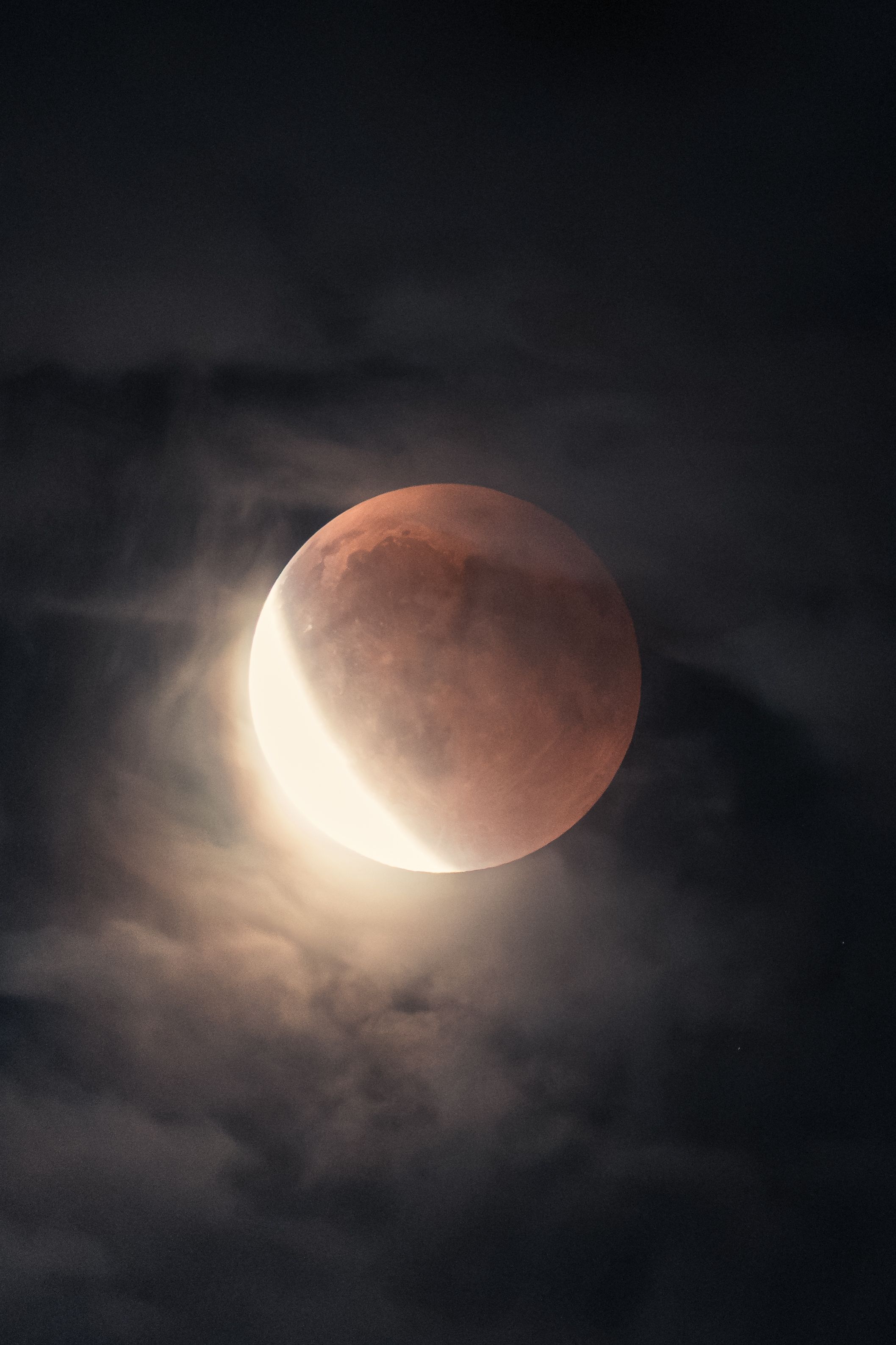 Capture of a stunning lunar eclipse with illuminated clouds in Vienna's night sky.