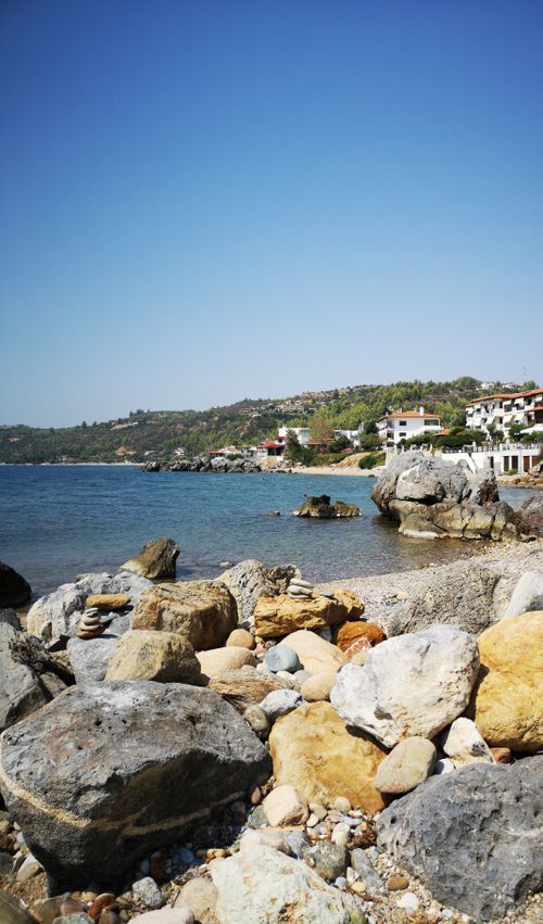 Free Tranquil view of a rocky Mediterranean shoreline with clear blue skies, perfect for travel inspiration. Stock Photo